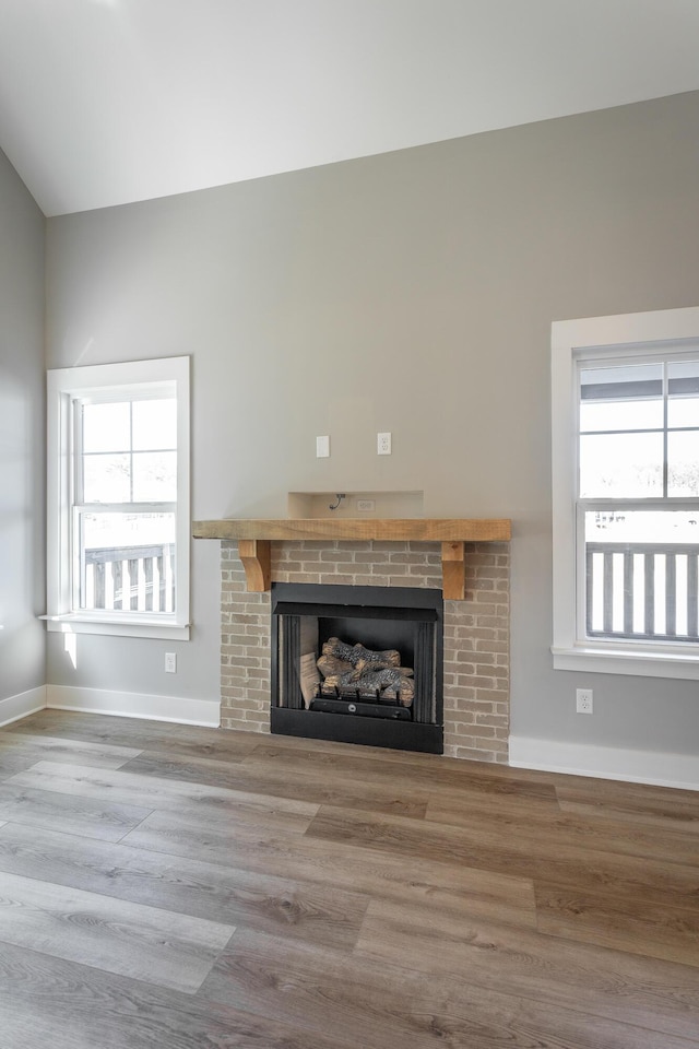 unfurnished living room with a brick fireplace, hardwood / wood-style floors, and a healthy amount of sunlight