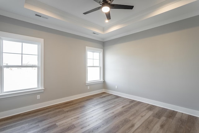 spare room with ceiling fan, crown molding, light wood-type flooring, and a tray ceiling