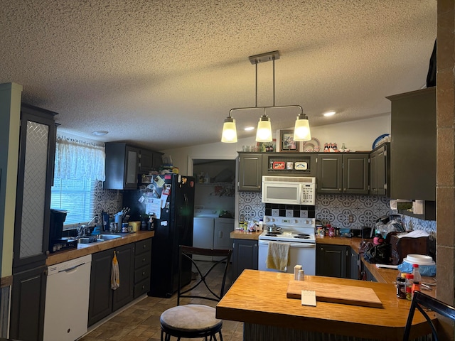 kitchen featuring pendant lighting, a textured ceiling, white appliances, and independent washer and dryer