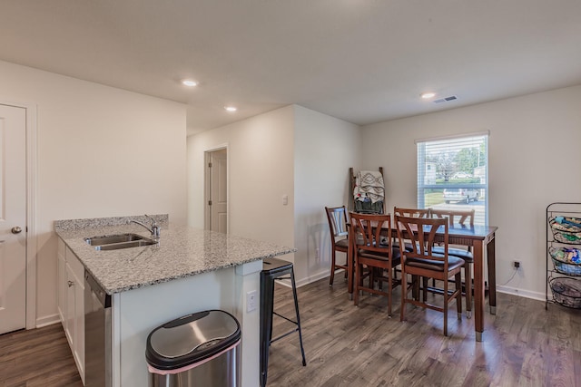 kitchen featuring light stone countertops, dark wood-type flooring, white cabinetry, sink, and kitchen peninsula