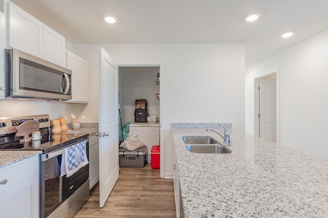 kitchen featuring sink, stainless steel appliances, white cabinetry, and light stone countertops