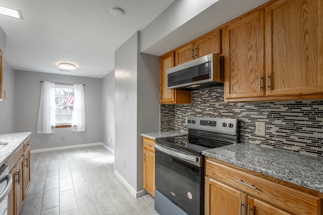 kitchen featuring decorative backsplash, light stone counters, and appliances with stainless steel finishes