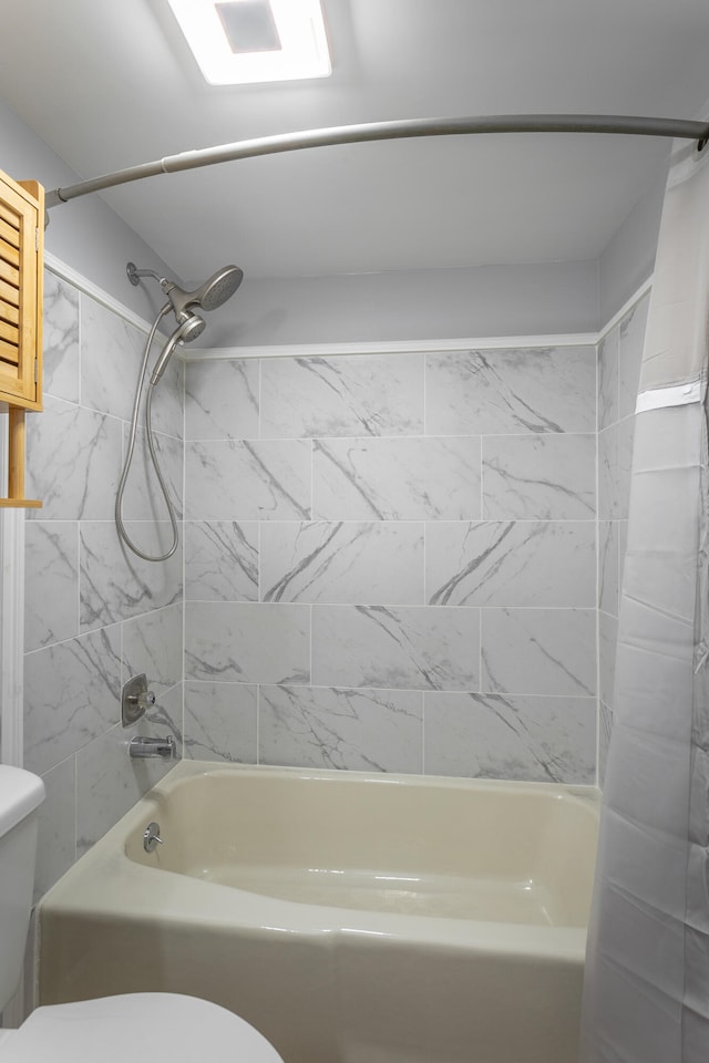 bathroom featuring tiled shower / bath combo and toilet