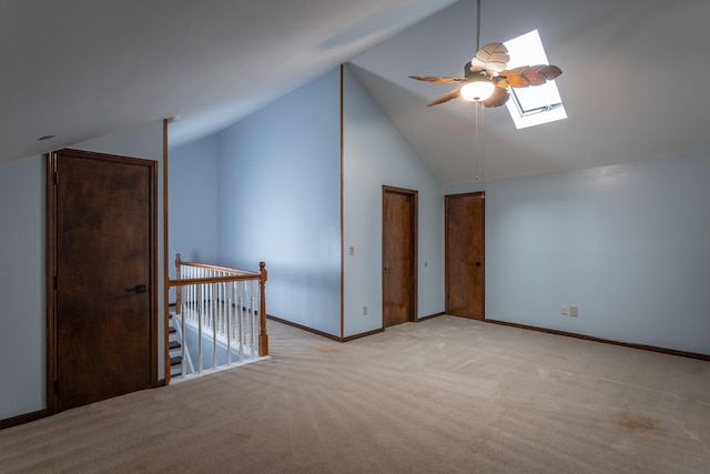 additional living space with lofted ceiling with skylight, light carpet, and ceiling fan