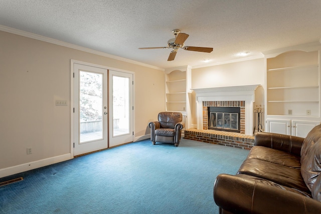 carpeted living room with french doors, crown molding, a textured ceiling, built in features, and a fireplace