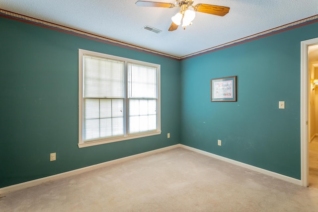 carpeted empty room with ceiling fan, ornamental molding, and a textured ceiling