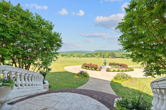 surrounding community featuring a patio area, a lawn, and a mountain view