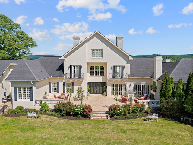 back of house featuring a lawn, a balcony, a patio, and an outdoor living space