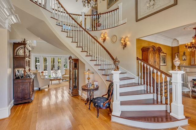 stairs featuring ornamental molding, a towering ceiling, hardwood / wood-style flooring, and french doors