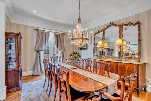 dining area with light wood-type flooring, a chandelier, and ornamental molding