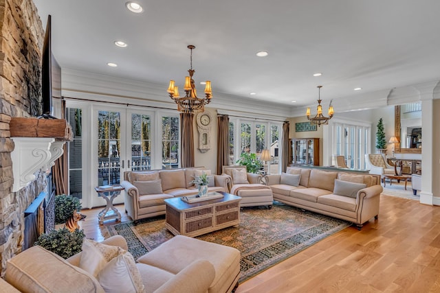 living room with a fireplace, an inviting chandelier, light wood-type flooring, and french doors