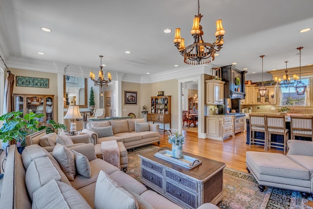 living room featuring ornamental molding, light hardwood / wood-style flooring, and an inviting chandelier