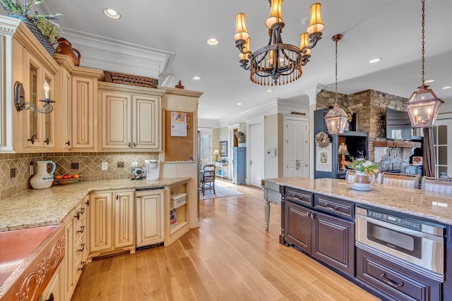 kitchen with light stone counters, ornamental molding, backsplash, decorative light fixtures, and light hardwood / wood-style floors