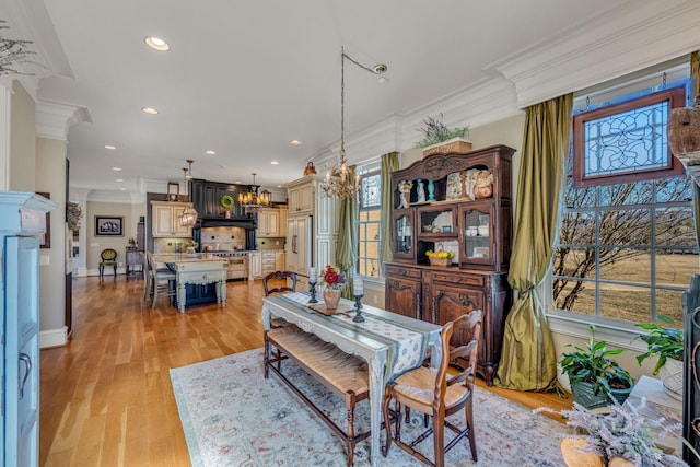 dining space featuring ornamental molding, light wood-type flooring, and an inviting chandelier