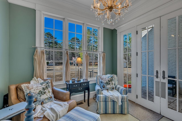 living area with ornamental molding, french doors, carpet floors, and a chandelier