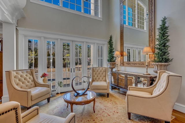 sitting room with a towering ceiling, wood-type flooring, and french doors