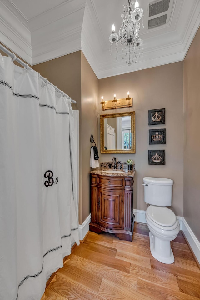 bathroom with crown molding, vanity, an inviting chandelier, hardwood / wood-style floors, and toilet