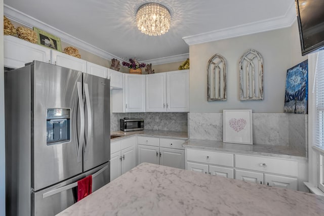 kitchen with white cabinetry, ornamental molding, backsplash, a chandelier, and stainless steel fridge