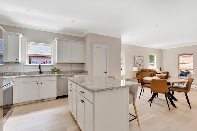 kitchen featuring backsplash, a kitchen island, a healthy amount of sunlight, and appliances with stainless steel finishes