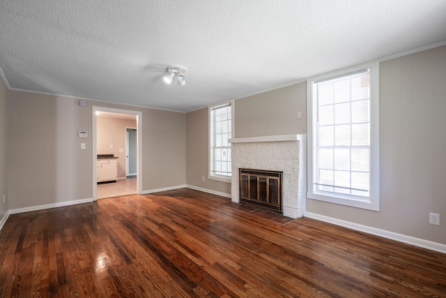 unfurnished living room with a fireplace, dark hardwood / wood-style flooring, a textured ceiling, and a wealth of natural light