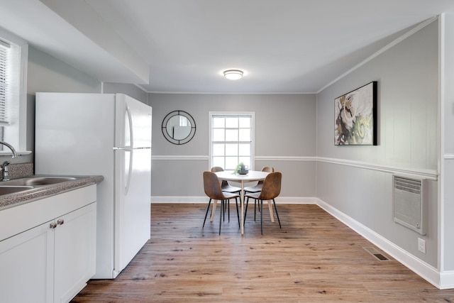 dining area featuring a wall unit AC, crown molding, light hardwood / wood-style flooring, and sink