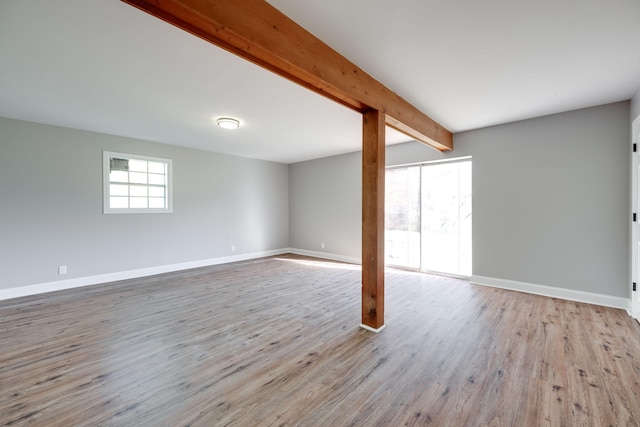 spare room featuring beamed ceiling and light wood-type flooring