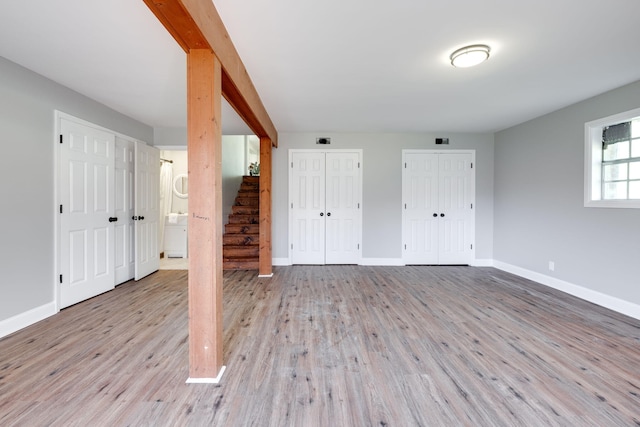 unfurnished bedroom featuring multiple closets, ensuite bathroom, and light hardwood / wood-style floors