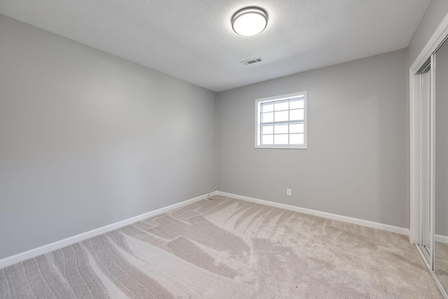 unfurnished room featuring light colored carpet and a textured ceiling