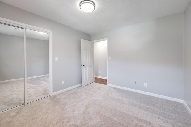 unfurnished bedroom with light colored carpet, a textured ceiling, and a closet