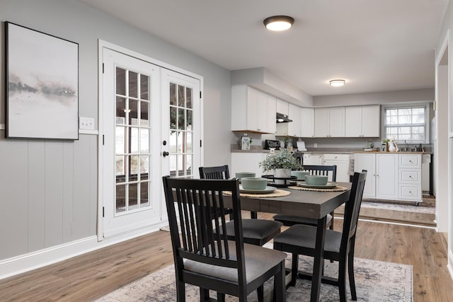 dining room with french doors, baseboards, and light wood finished floors