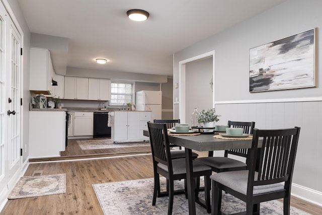 dining space with a wainscoted wall and wood finished floors