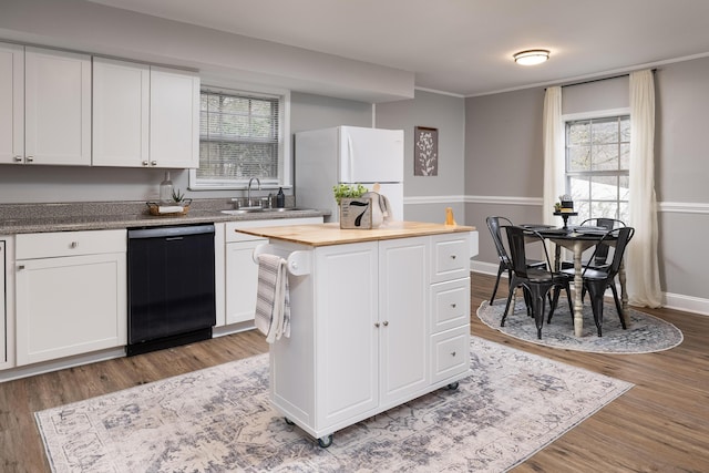 kitchen featuring white cabinets, dishwasher, a kitchen island, freestanding refrigerator, and a sink