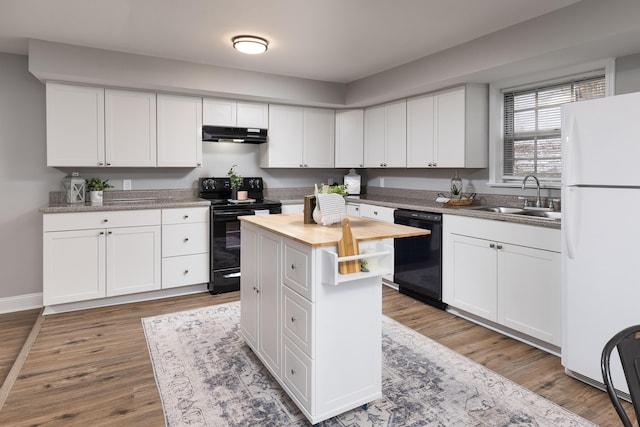 kitchen with black appliances, a kitchen island, white cabinets, and a sink