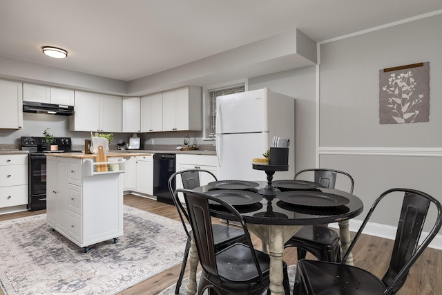 kitchen with black appliances, wood finished floors, under cabinet range hood, and white cabinets