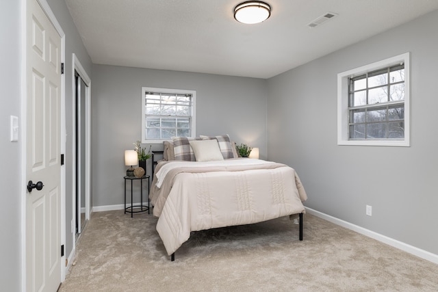 bedroom with visible vents, light carpet, and baseboards