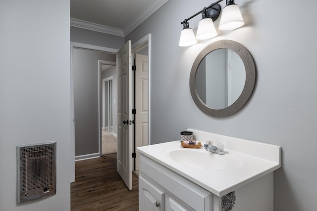 bathroom with wood finished floors, heating unit, vanity, and crown molding