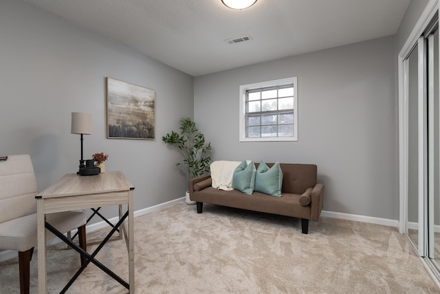 office space with visible vents, light carpet, and baseboards