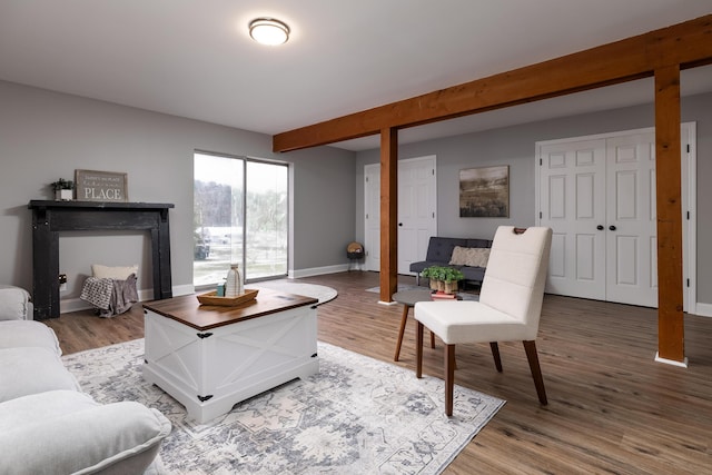 living area with beamed ceiling, baseboards, and wood finished floors