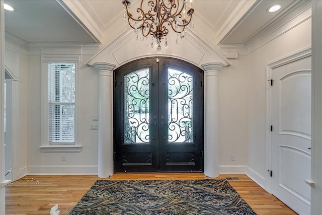 entrance foyer with light hardwood / wood-style floors, ornate columns, and french doors