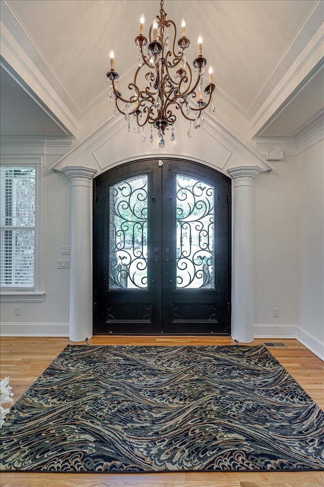 foyer with wood-type flooring, crown molding, and french doors