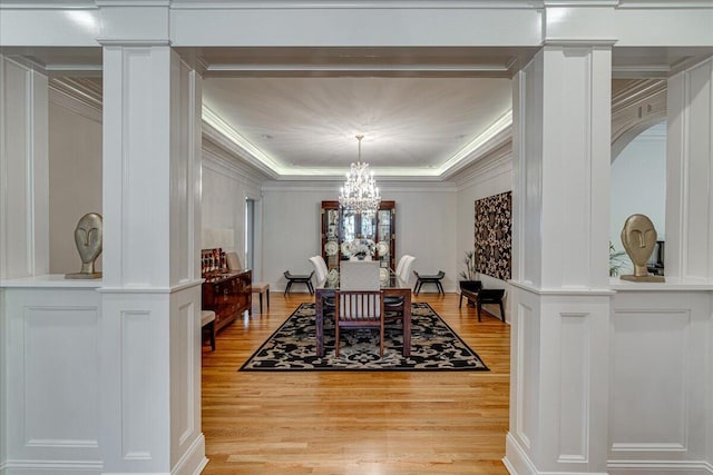 dining room featuring light wood-type flooring, ornate columns, and crown molding