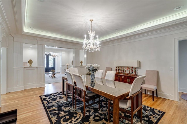 dining area with a tray ceiling, crown molding, light hardwood / wood-style flooring, and a chandelier