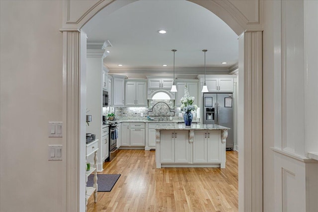 kitchen with a center island, hanging light fixtures, light hardwood / wood-style floors, white cabinets, and appliances with stainless steel finishes