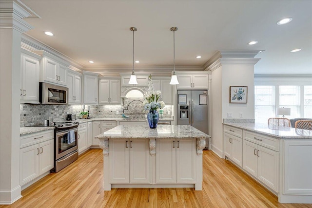 kitchen with pendant lighting, light hardwood / wood-style floors, white cabinetry, and appliances with stainless steel finishes