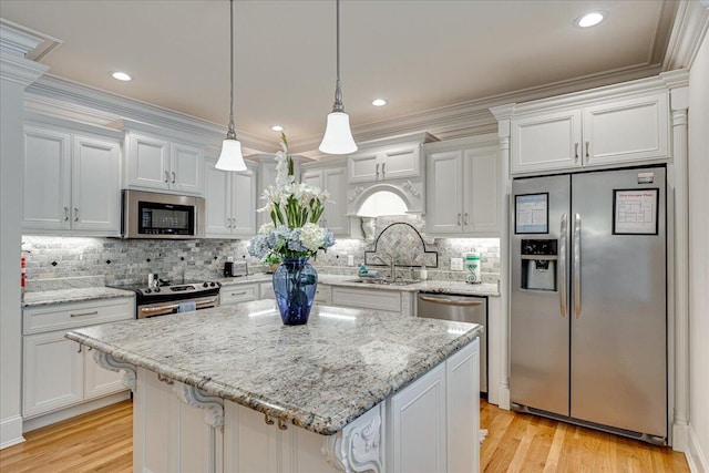 kitchen featuring light wood-type flooring, stainless steel appliances, pendant lighting, a center island, and white cabinetry