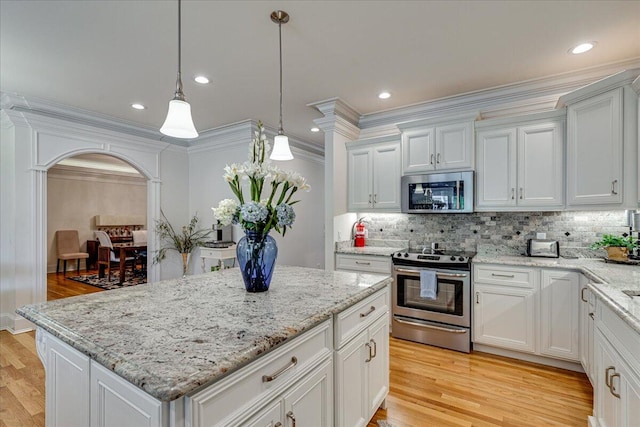 kitchen with white cabinets, light hardwood / wood-style floors, a kitchen island, and stainless steel appliances