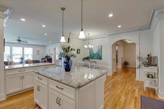 kitchen with crown molding, a kitchen island, and light wood-type flooring