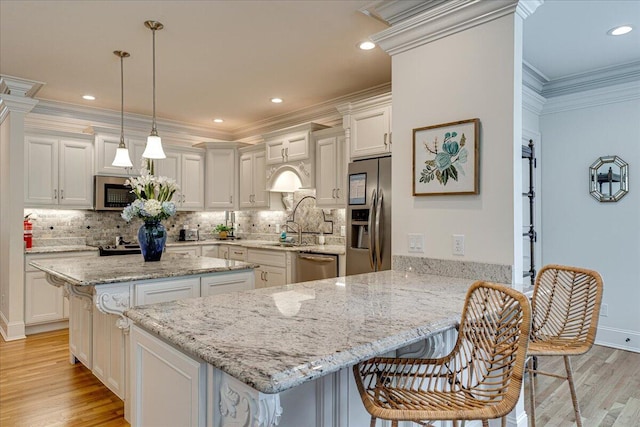 kitchen featuring kitchen peninsula, appliances with stainless steel finishes, light hardwood / wood-style flooring, white cabinetry, and hanging light fixtures