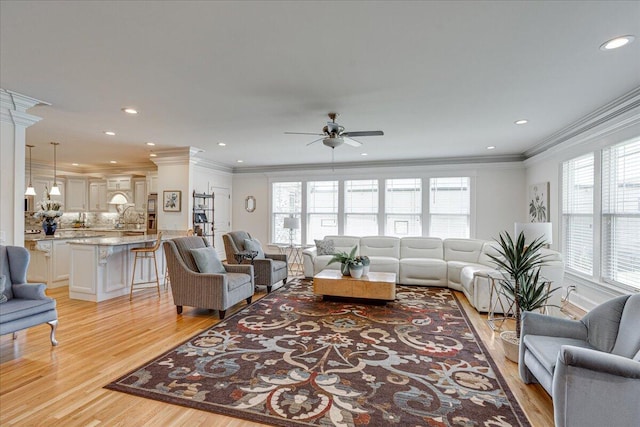 living room featuring decorative columns, ceiling fan, light hardwood / wood-style floors, and ornamental molding