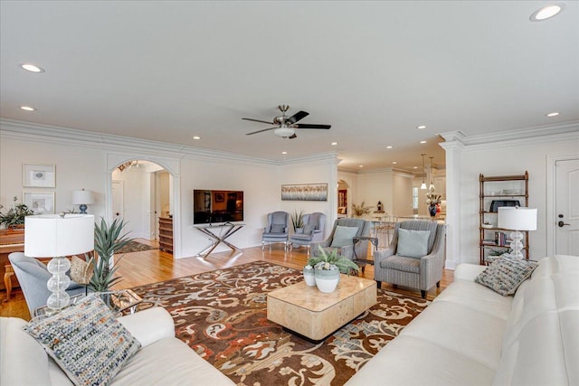 living room with ceiling fan with notable chandelier, hardwood / wood-style flooring, and ornamental molding